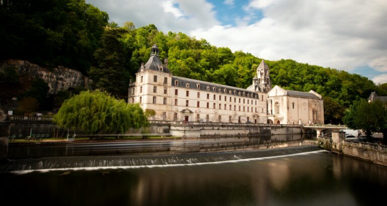 Abbaye de Brantôme avec une petite cascade (déversoir) sur la Dronne au premier plan